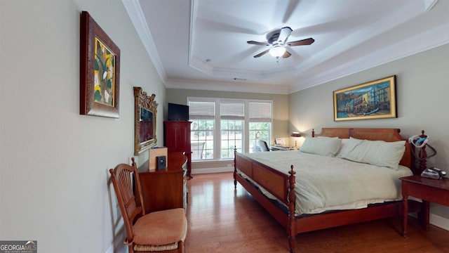 bedroom featuring ceiling fan, dark hardwood / wood-style floors, a raised ceiling, and crown molding