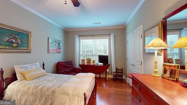 bedroom with ornamental molding, dark hardwood / wood-style flooring, ceiling fan, and a closet