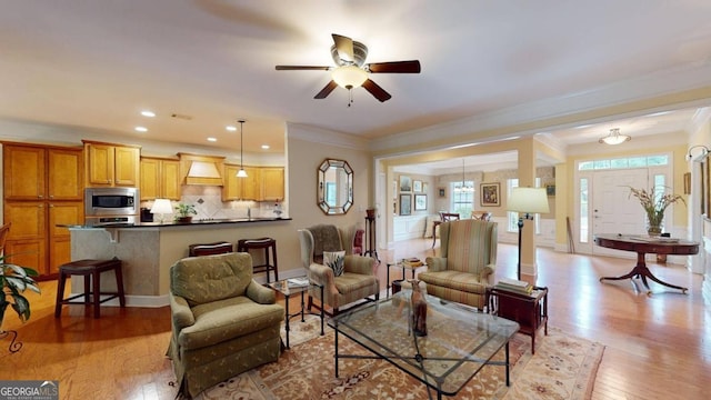 living room with crown molding, ceiling fan, and light hardwood / wood-style floors