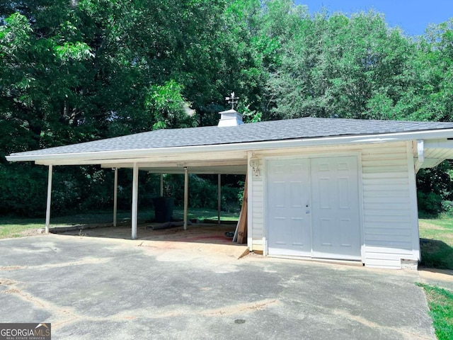 exterior space with aphalt driveway, an outbuilding, and a carport