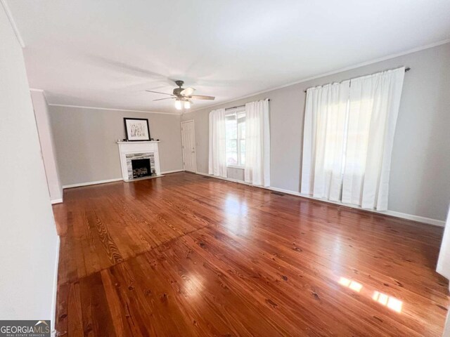 unfurnished living room with ceiling fan, ornamental molding, and wood-type flooring