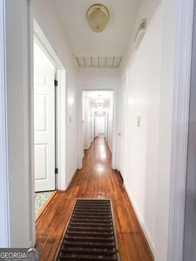 hallway featuring ornamental molding, wood finished floors, visible vents, and baseboards