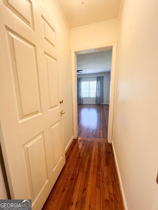 hallway with dark wood-type flooring, a paneled ceiling, and baseboards