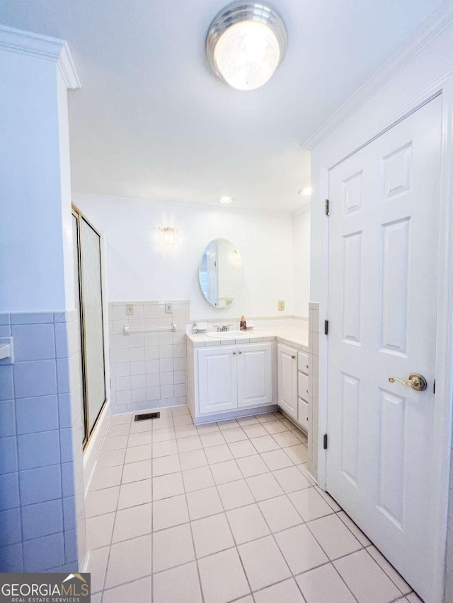 full bath with a shower with door, tile walls, visible vents, vanity, and tile patterned flooring