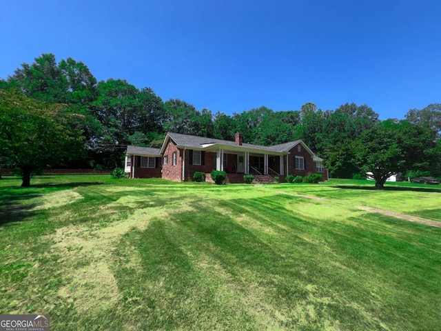 ranch-style home with brick siding, a chimney, and a front yard