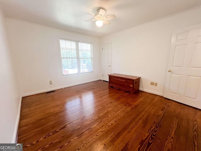 interior space with ceiling fan, ornamental molding, and dark hardwood / wood-style flooring