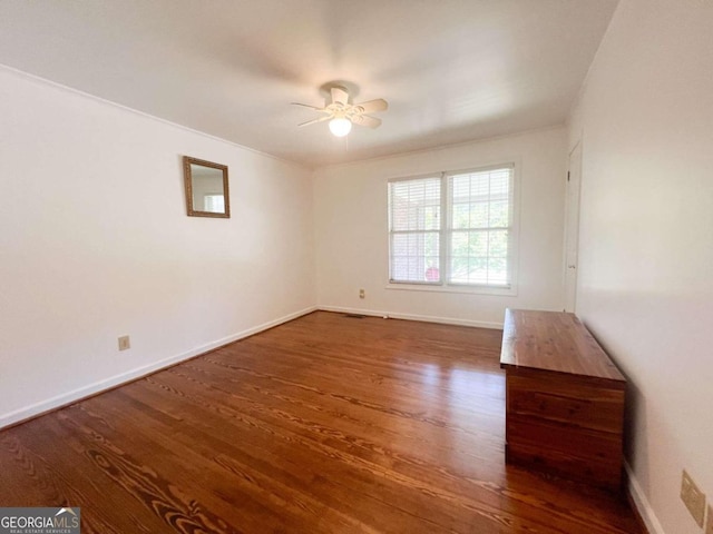 empty room featuring wood finished floors, a ceiling fan, and baseboards