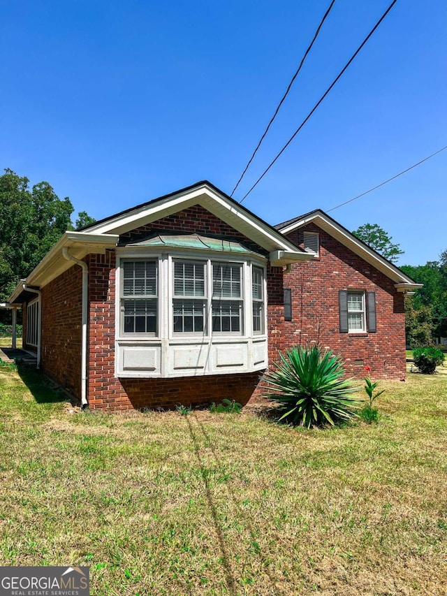 view of property exterior featuring brick siding and a yard