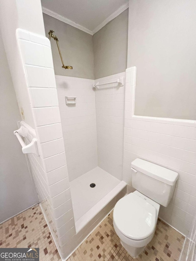 bathroom with tile patterned flooring, crown molding, walk in shower, toilet, and tile walls