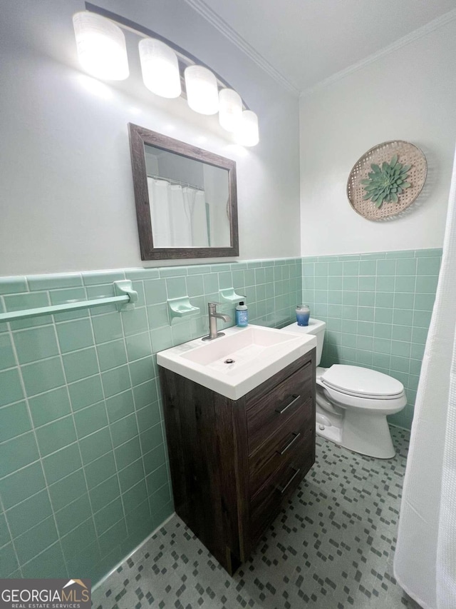 bathroom featuring a wainscoted wall, crown molding, tile walls, toilet, and vanity