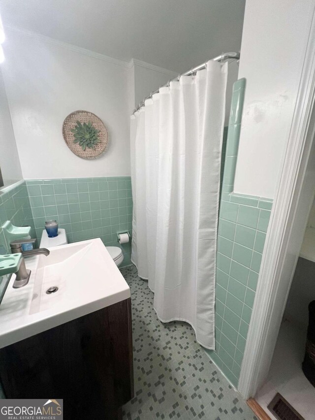 bathroom with tile patterned flooring, walk in shower, tile walls, vanity, and ornamental molding