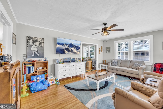 living room featuring a textured ceiling, ceiling fan, ornamental molding, and hardwood / wood-style floors