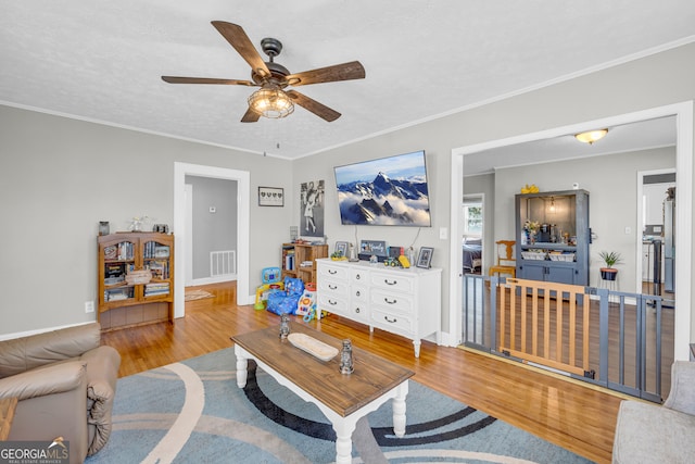 living room with light wood-type flooring, crown molding, a textured ceiling, and ceiling fan