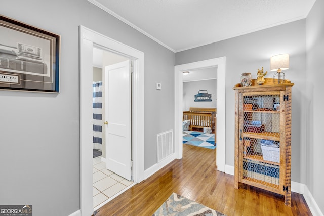 corridor with ornamental molding and light hardwood / wood-style floors