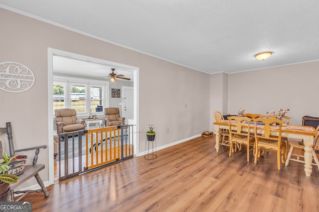 dining room with ornamental molding, a textured ceiling, wood-type flooring, and ceiling fan