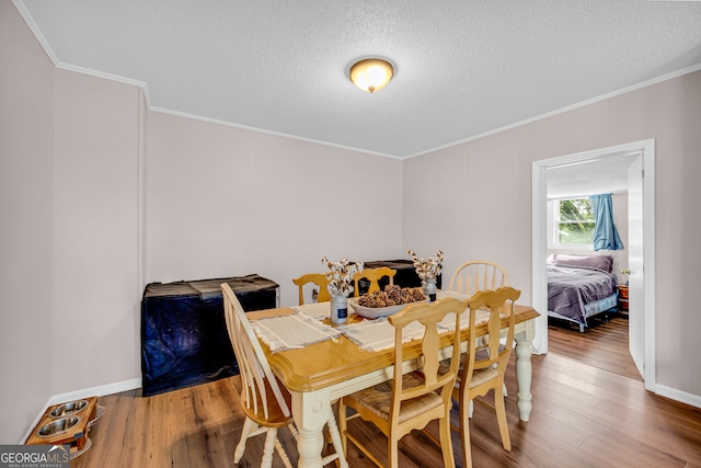 dining area featuring light wood-type flooring, crown molding, and a textured ceiling