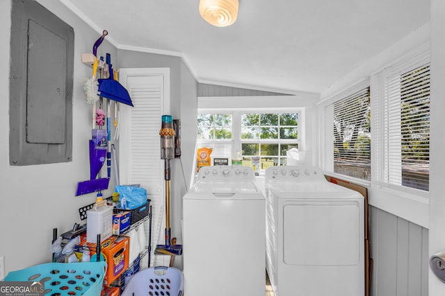 laundry area with electric panel, washing machine and dryer, ornamental molding, and wooden walls