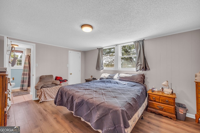 bedroom with wood-type flooring, connected bathroom, and a textured ceiling