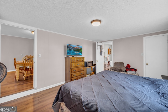 bedroom with a textured ceiling, crown molding, and wood-type flooring