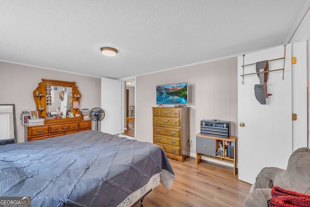 bedroom with light wood-type flooring, crown molding, and a textured ceiling