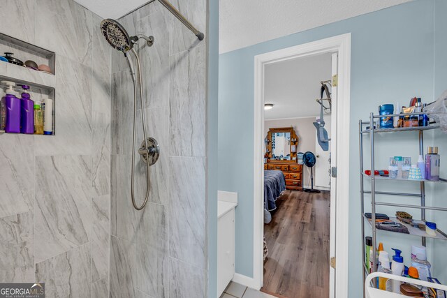 bathroom with hardwood / wood-style flooring, a textured ceiling, and a tile shower