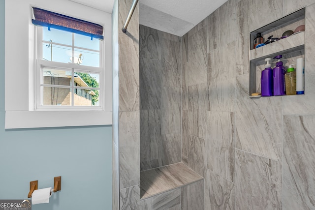 bathroom featuring a textured ceiling and a tile shower