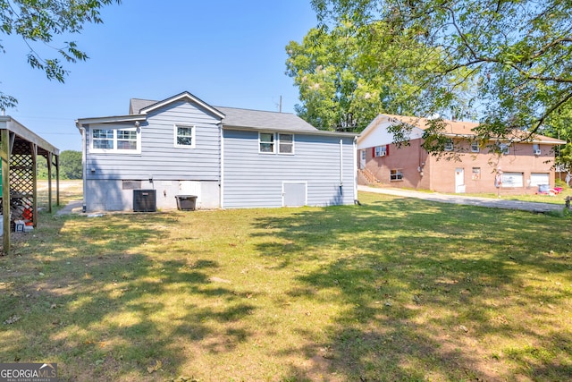 rear view of property with central AC unit and a lawn