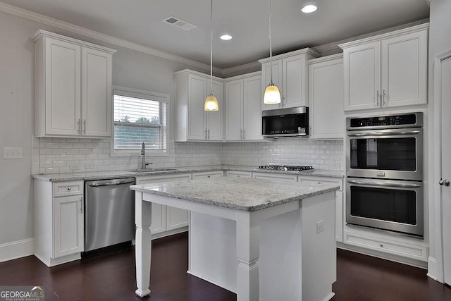 kitchen with stainless steel appliances, sink, decorative light fixtures, a center island, and white cabinetry