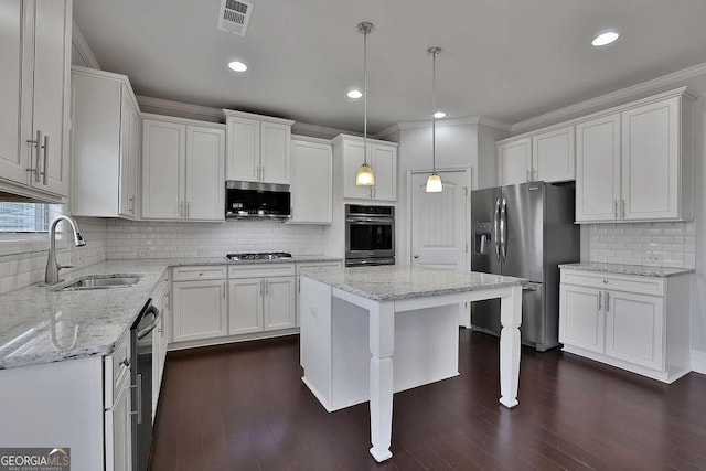 kitchen featuring sink, appliances with stainless steel finishes, decorative light fixtures, a kitchen island, and white cabinetry