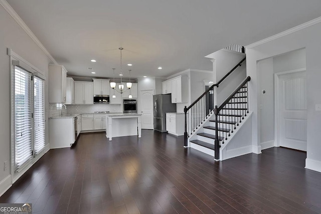 kitchen featuring hanging light fixtures, stainless steel appliances, a kitchen island, dark hardwood / wood-style floors, and white cabinets