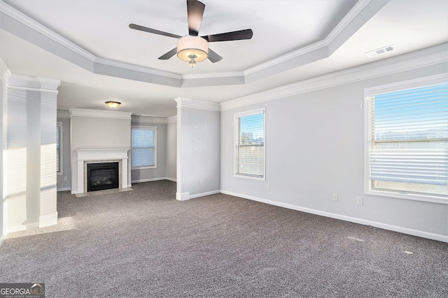 unfurnished living room featuring carpet, a raised ceiling, crown molding, and a wealth of natural light