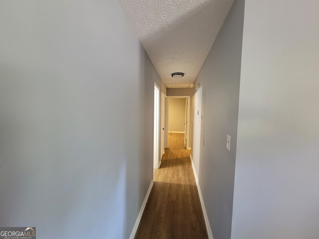 corridor featuring a textured ceiling and hardwood / wood-style floors