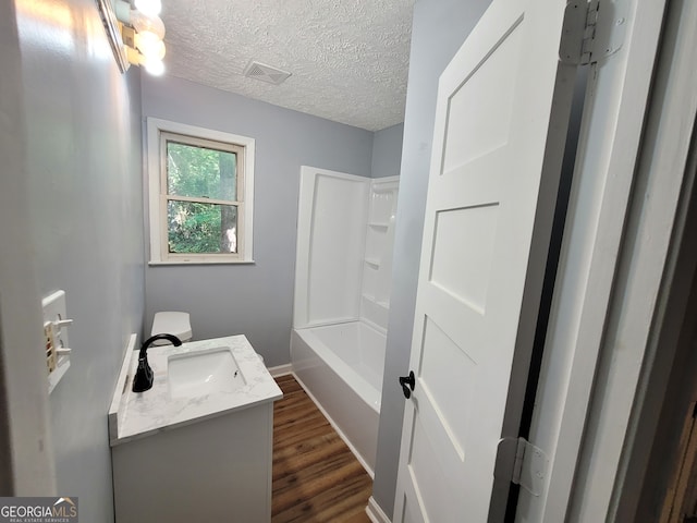 bathroom with bathtub / shower combination, hardwood / wood-style flooring, a textured ceiling, and vanity