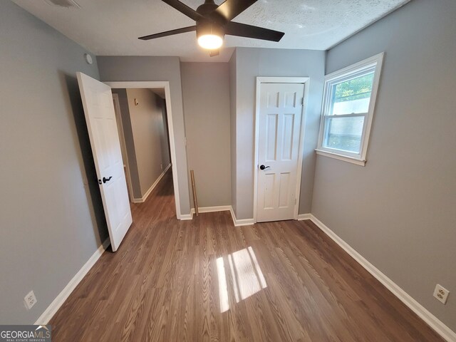 unfurnished bedroom with a textured ceiling, ceiling fan, and hardwood / wood-style floors