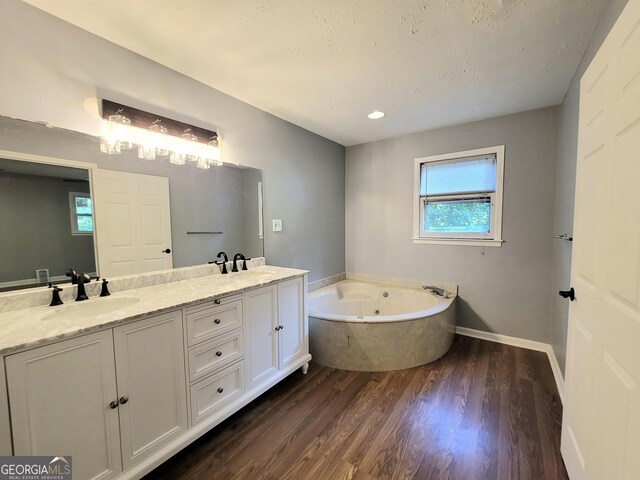 bathroom with vanity, a bath, hardwood / wood-style floors, and a textured ceiling