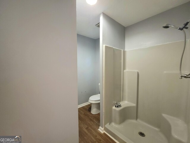 bathroom with a shower, wood-type flooring, and toilet