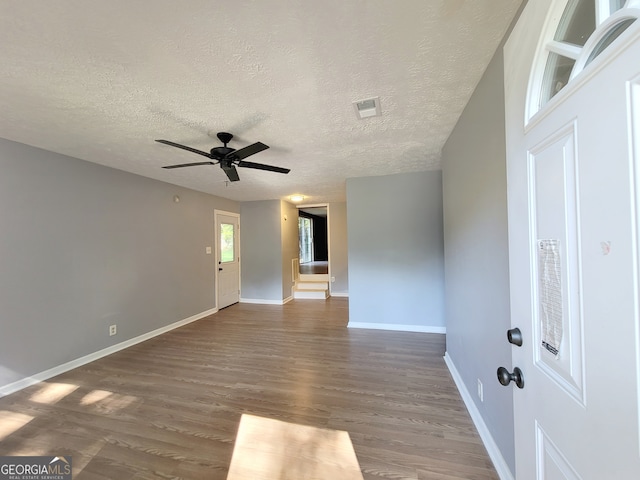 unfurnished room featuring a textured ceiling, ceiling fan, and dark hardwood / wood-style floors