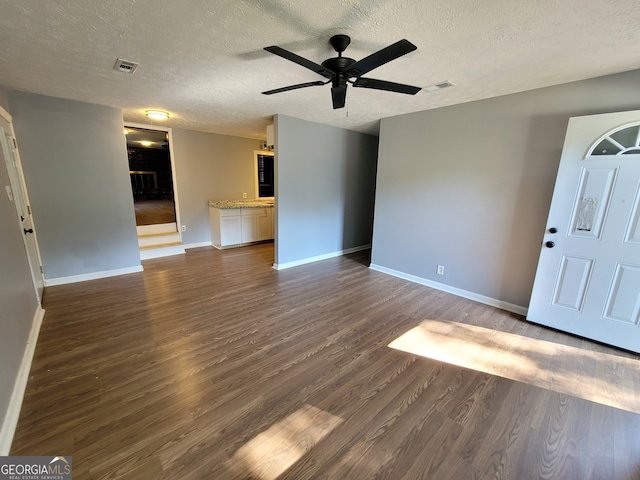 unfurnished living room with a textured ceiling, ceiling fan, and dark hardwood / wood-style flooring