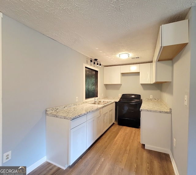 kitchen featuring light wood-type flooring, white cabinets, light stone countertops, and electric range