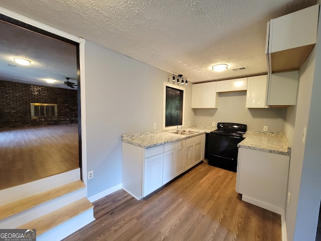 kitchen with a fireplace, white cabinetry, black electric range oven, and ceiling fan