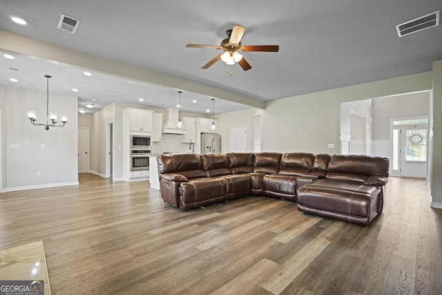 living room with recessed lighting, visible vents, and light wood finished floors