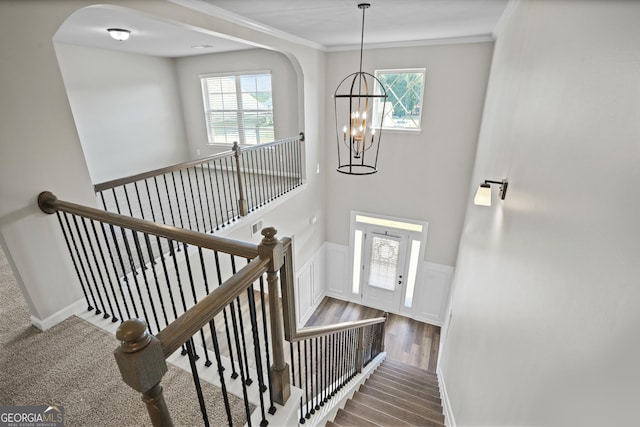 stairs with a wainscoted wall, plenty of natural light, and ornamental molding