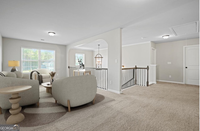 carpeted living room featuring a notable chandelier, visible vents, attic access, and baseboards