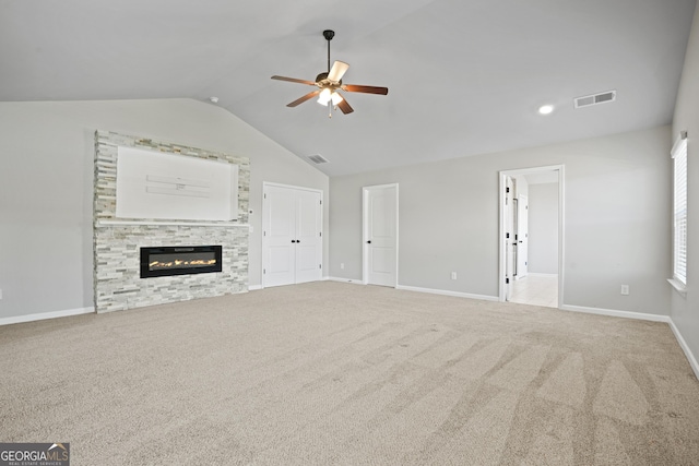 unfurnished living room featuring visible vents, vaulted ceiling, carpet flooring, a stone fireplace, and a ceiling fan