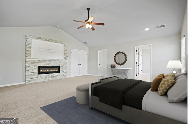 carpeted bedroom featuring visible vents, baseboards, lofted ceiling, and a glass covered fireplace