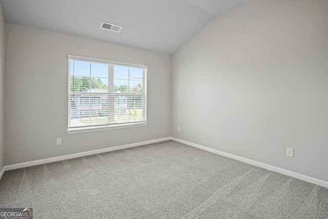 carpeted spare room with vaulted ceiling, baseboards, and visible vents