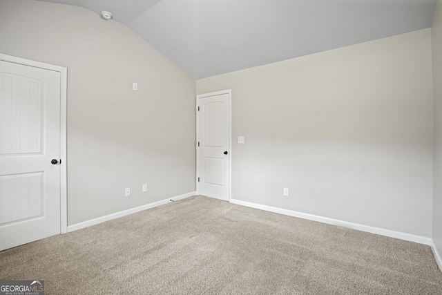 carpeted empty room featuring lofted ceiling and baseboards