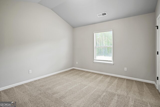 unfurnished room featuring lofted ceiling, baseboards, visible vents, and light carpet