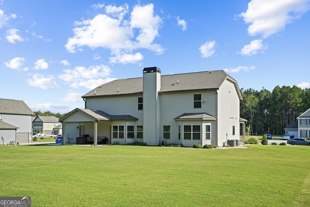 rear view of property featuring central air condition unit, a lawn, roof with shingles, and a chimney