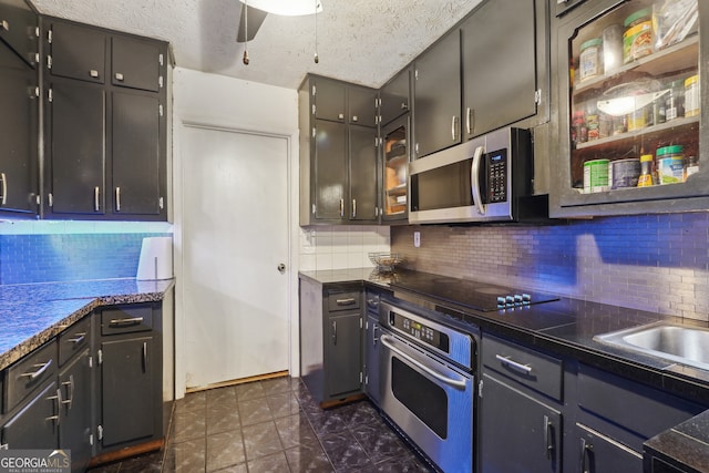 kitchen featuring ceiling fan, a textured ceiling, appliances with stainless steel finishes, and tasteful backsplash